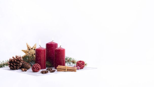 Christmas Candles on white, Weihnachtsdekoration auf weissem Hintergrund. Rote, brennende Kerzen, Zimtstangen und Zweige - Foto, Imagem