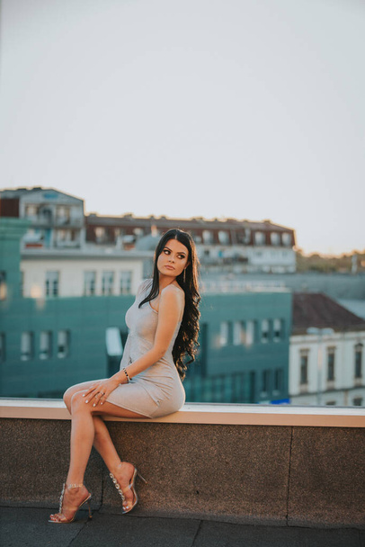 A vertical shot of a brunette female posing at a terrace - Zdjęcie, obraz