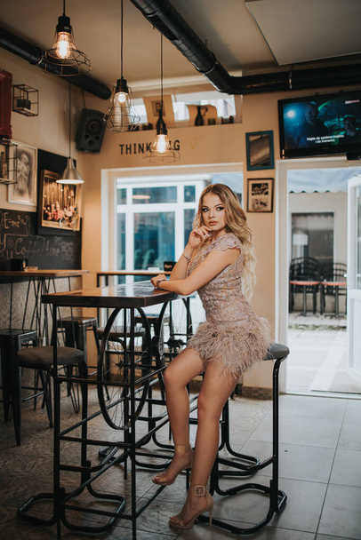 A young glamour woman in dress and blonde hair posing in a cafe - Φωτογραφία, εικόνα