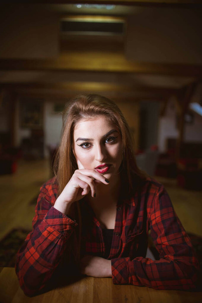 A blonde Caucasian female with a red checkered shirt posing at the camera - Фото, изображение