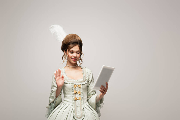 вінтажний стиль жінка махає рукою під час відеодзвінка на цифровому планшеті ізольовано на сірому
 - Фото, зображення