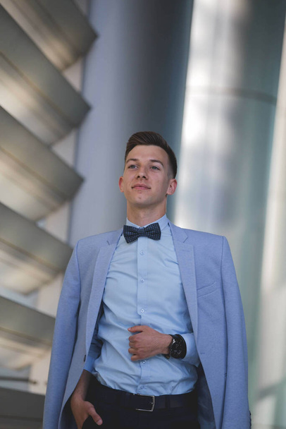 A vertical shot of a Caucasian male with a suit posing outdoors - Фото, изображение