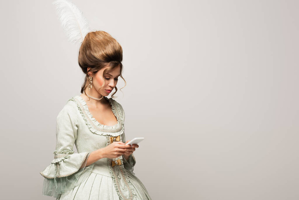 femme élégante en robe vintage messagerie sur smartphone isolé sur gris - Photo, image
