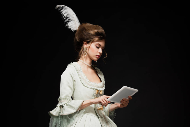 fiatal nő elegáns vintage ruha segítségével digitális tabletta elszigetelt fekete - Fotó, kép