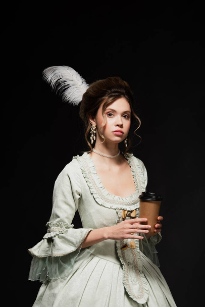 charming vintage style woman with disposable cup looking at camera isolated on black - Fotoğraf, Görsel