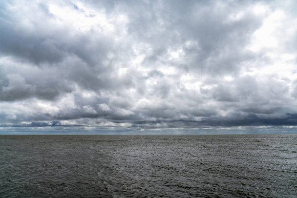 Bewölkter Himmel über dem windgepeitschten Wattenmeer der Niederlande - Foto, Bild