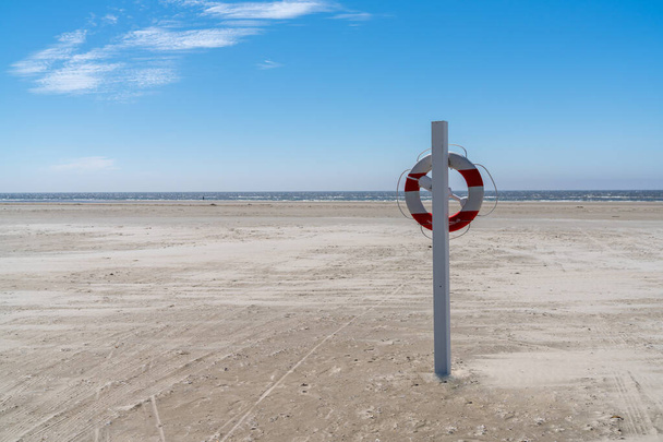 спасательная станция и флотационное кольцо на бесконечном песчаном пляже на Ваттовом побережье острова моря западной Дании - Фото, изображение