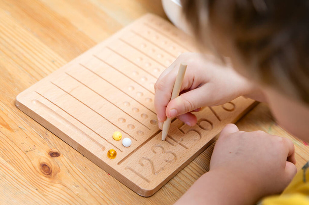 Montessori Perlen Board. Lernen, Zahlen zu zählen und zu schreiben, Kinder auf geistiges Rechnen vorzubereiten, Ordnungssinn, Konzentration, Koordination und Genauigkeit zu entwickeln. - Foto, Bild
