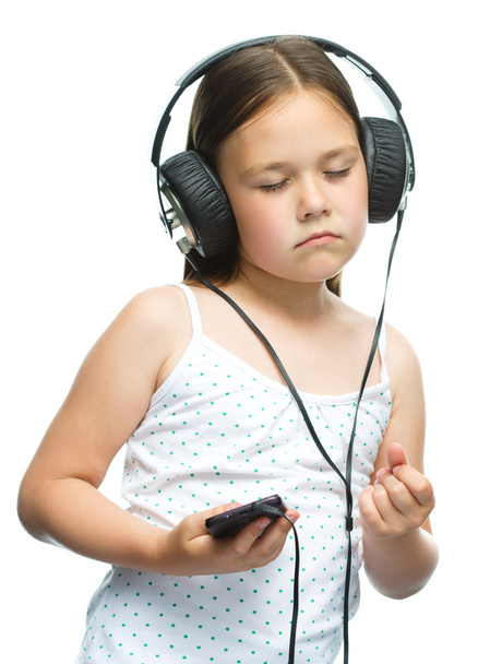 μικρό κορίτσι απολαμβάνει τη μουσική χρησιμοποιώντας ακουστικά - Φωτογραφία, εικόνα