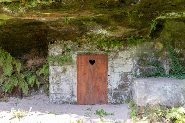 Maalaismainen puinen wc vuorella sydämen muotoinen reikä oven levyt. Puinen ulkokäymälä luonnossa - Valokuva, kuva