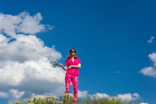 jovem menina bonita em rosa em um fundo de nuvens no céu azul verão. - Foto, Imagem