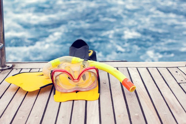 夏のコンセプト。海の景色。ボートに残されたダイビングマスクとフリッパー. - 写真・画像