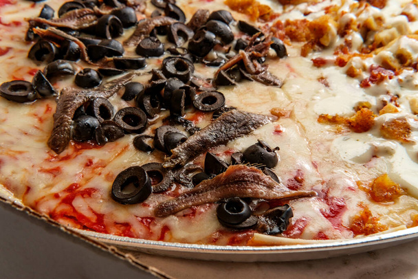 Нью-Йоркский стиль пиццы наполовину анчоусы и черные оливки и другая половина куриного бекона начинки ранчо - Фото, изображение