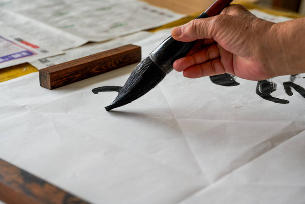 A calligrapher is writing calligraphy characters with a large brush, a close-up of the brush. Translation: The heights are too cold - Φωτογραφία, εικόνα