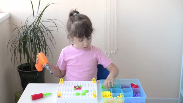 detailní záběr dítěte, které si hraje na dětského konstruktéra se šroubovákem, šroubovákem a šurukami s barevnými geometrickými fíky. koncepce kreativního předškolního vývoje - Záběry, video