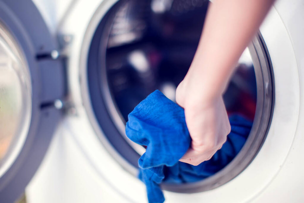 Крупним планом рука людини покласти брудний одяг в пральну машину для прання
 - Фото, зображення