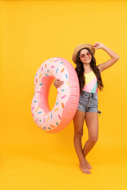 happy beach child with curly hair in straw hat and sunglasses with doughnut inflatable ring for pool party fun on summer vacation on yellow background, summer holiday. - Photo, Image