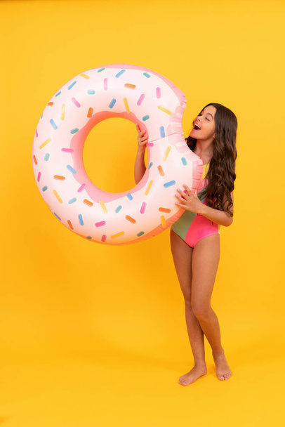 child hold beach accessory of inflatable circle. active childhood. summertime kid weekend. sunbathing. summer vacation. happy girl in swimsuit inflatable doughnut ring. teen with swimming ring. - Foto, Imagem