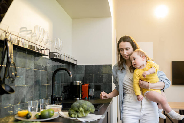 Žena zaneprázdněná domácími pracemi při kojení svého dítěte - Fotografie, Obrázek