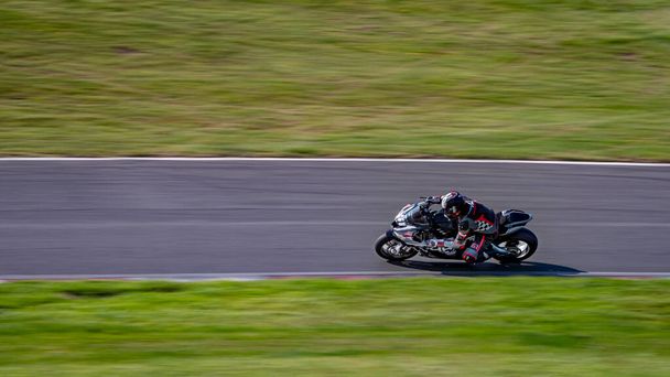 панорамный снимок гоночного мотоцикла, когда он обходит трассу. - Фото, изображение