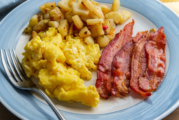 Comida americana desayuno huevos revueltos con papas fritas caseras y tocino crujiente - Foto, imagen