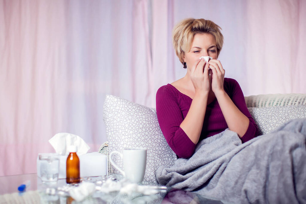 Woman with short blond hair got the flu and blowing nose into napkin. People, healthcare and medicine concept - Фото, зображення