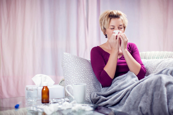 Woman with short blond hair got the flu and blowing nose into napkin. People, healthcare and medicine concept - Foto, imagen