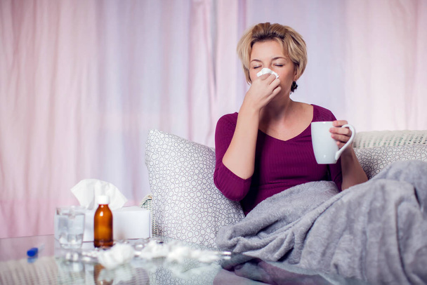 Woman with short blond hair got the flu and blowing nose into napkin. People, healthcare and medicine concept - Фото, изображение
