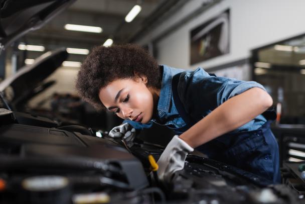 jeune mécanicien afro-américain moteur de fixation dans la voiture avec capot ouvert dans le garage - Photo, image