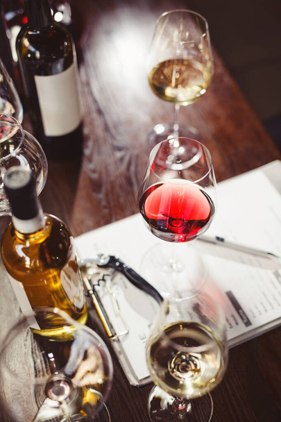 Wineglasses and wine bottles around clipboard on table - Fotó, kép