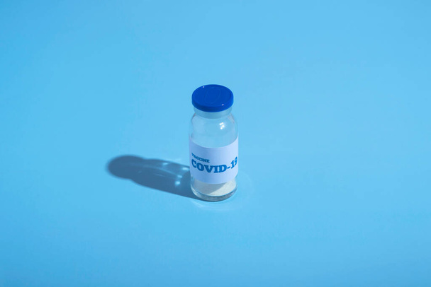 Ampoule of covid-19 vaccine. Coronavirus treatment, pandemic control. Blue background, copy space. Vaccination concept. Medicine - Fotó, kép