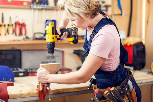 Young smiling handy woman with short blond hair working with screwdriver.  - Foto, Imagem