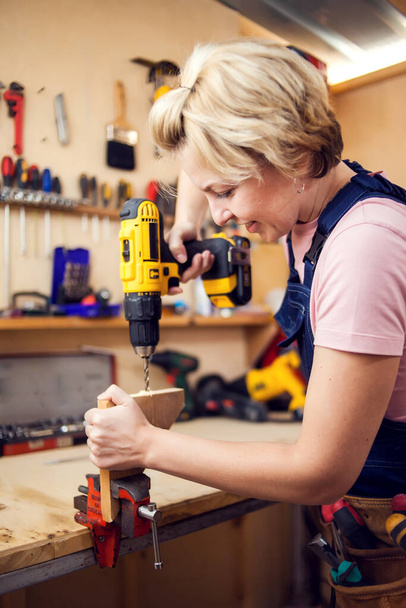 Young smiling handy woman with short blond hair working with screwdriver.  - Valokuva, kuva