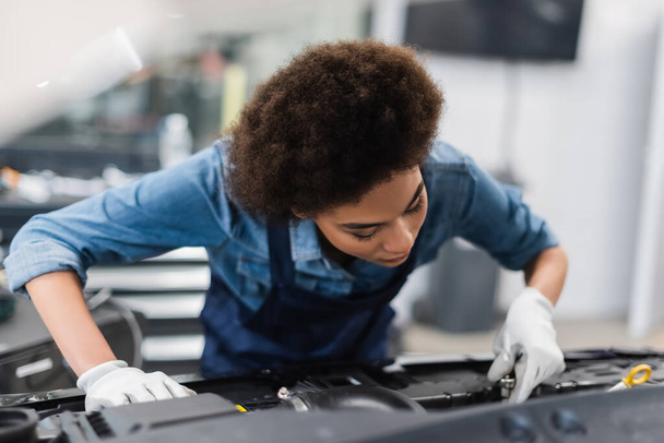 Genç Afro-Amerikan tamirci garajda araba motoru tamir ediyor. - Fotoğraf, Görsel