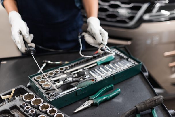 close up view of mechanic hands in gloves holding diagnostic equipment near toolbox in garage - Photo, Image