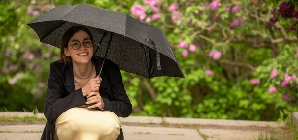 Κορίτσι κάτω από μια μαύρη ομπρέλα στη βροχή. - Φωτογραφία, εικόνα
