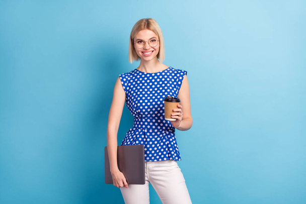 Photo of young attractive girl happy positive smile hold laptop drink coffee break pause isolated over blue color background - Valokuva, kuva