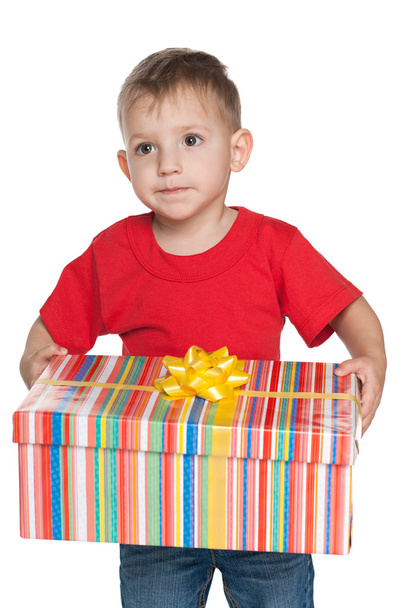 Pensive little boy holds a gift box - Zdjęcie, obraz