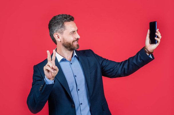 happy businessman making selfie. male business blogger. vlogger with cellphone show peace gesture. - Fotoğraf, Görsel