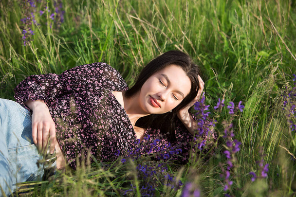 若いですリラックスした女の子は夏の日に野の花の間に横たわって休息を楽しんでいます. - 写真・画像