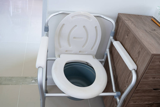 Крісло-комод або мобільний туалет може переміщатися в спальні або скрізь для літніх людей похилого віку або пацієнта в лікарні, здорове сильне медичне поняття
 - Фото, зображення