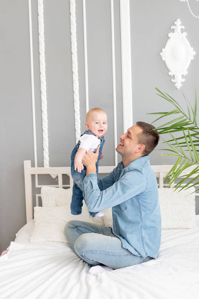 счастливая семья, папа, играющий с ребенком дома на кровати, концепция дня отца или счастливое отцовство - Фото, изображение