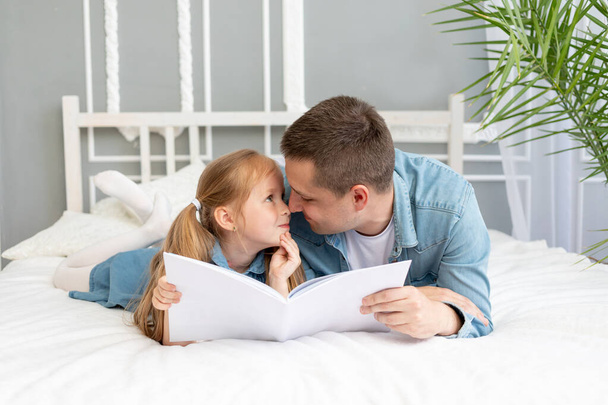 o pai lê um livro ou estuda com o filho da filha antes de ir para a cama ou se divertir - Foto, Imagem