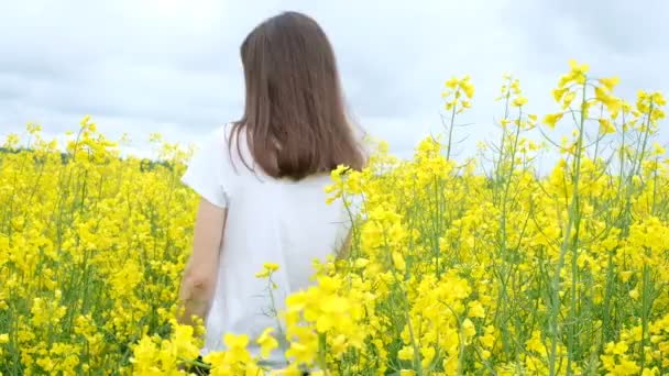 Jonge vrouw in een wit t-shirt tussen een veld van gele bloemen - Video