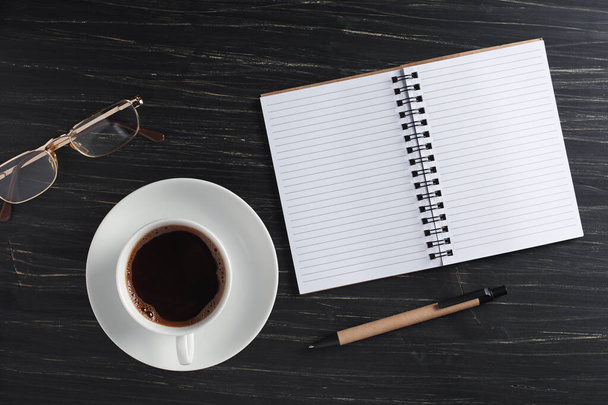 Cup of coffee and eco-friendly notebook with pen on black table, top view - Foto, Imagem