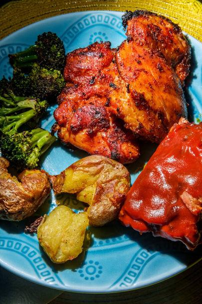 Plate of BBQ ja grillattua ruokaa, mukaan lukien murskattuja perunoita Memphis hierotaan kanan reidet hiiltynyt parsakaali ja röyhkeä kylkiluut - Valokuva, kuva