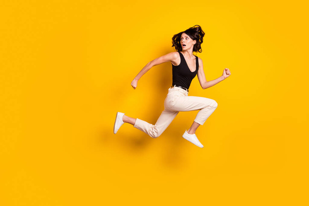 Full length body size side profile photo of crazy woman jumping running away looking back isolated bright yellow color background - Φωτογραφία, εικόνα