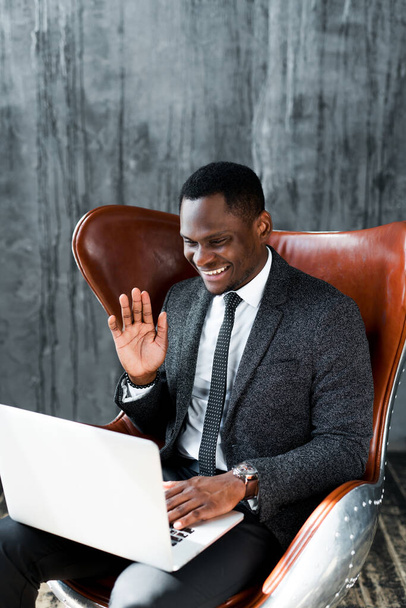 Happy african american businessman chatting on skype on laptop waving hand and smiling - Fotoğraf, Görsel