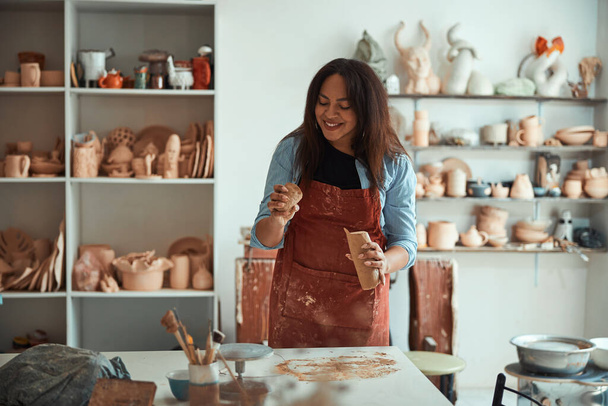Очаровательная молодая женщина, работающая в керамической мастерской - Фото, изображение