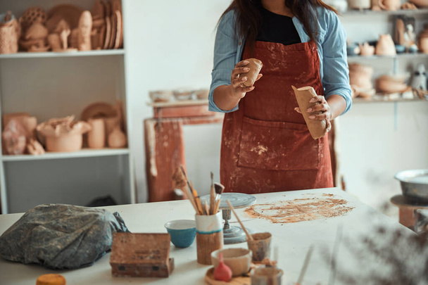 Γυναίκα κεραμίστρια με ποδιά που εργάζεται σε στούντιο κεραμικής - Φωτογραφία, εικόνα